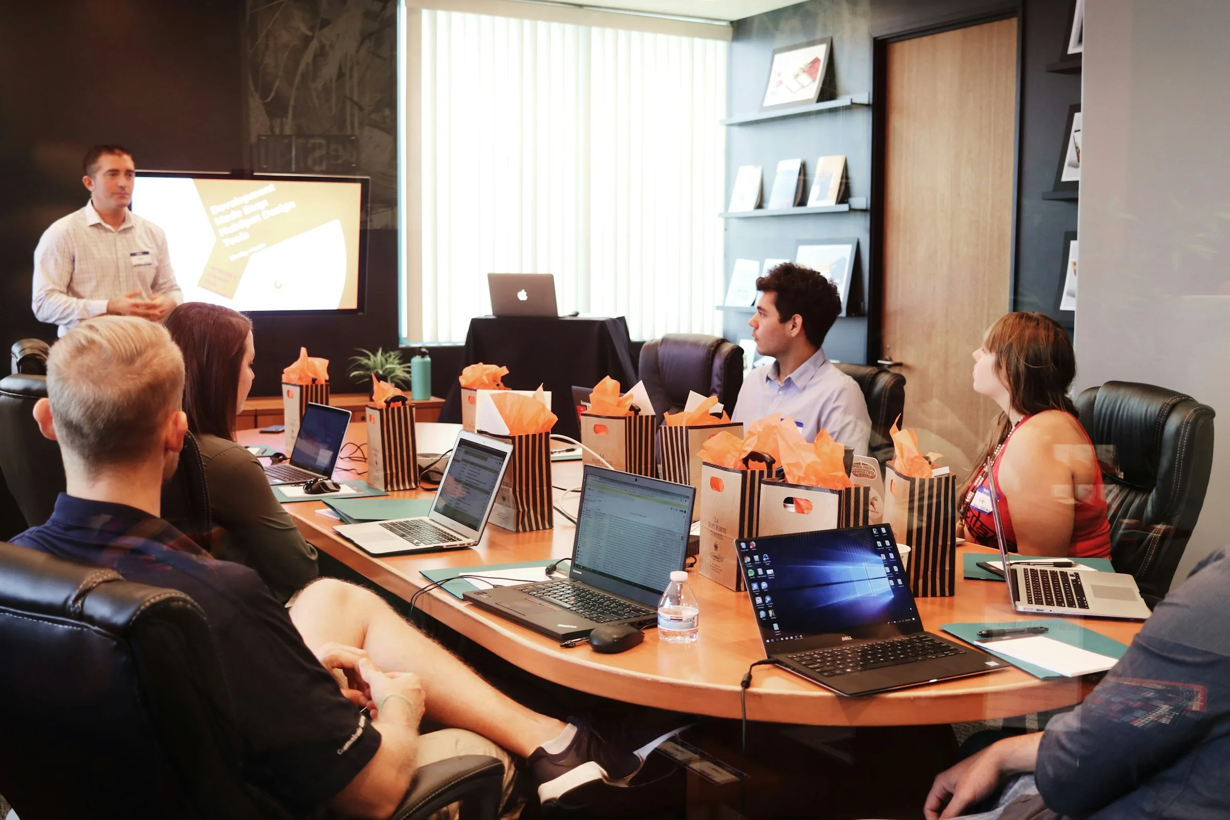 A team meeting around a boardroom table with laptops